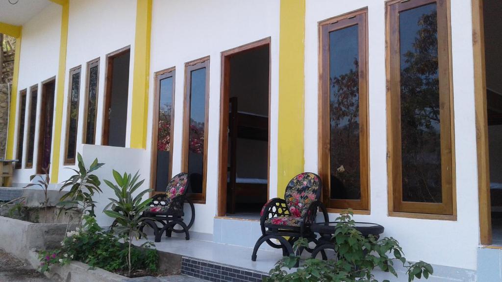drei Bänke vor einem Gebäude mit Fenstern in der Unterkunft Tarsan Homestay in Labuan Bajo