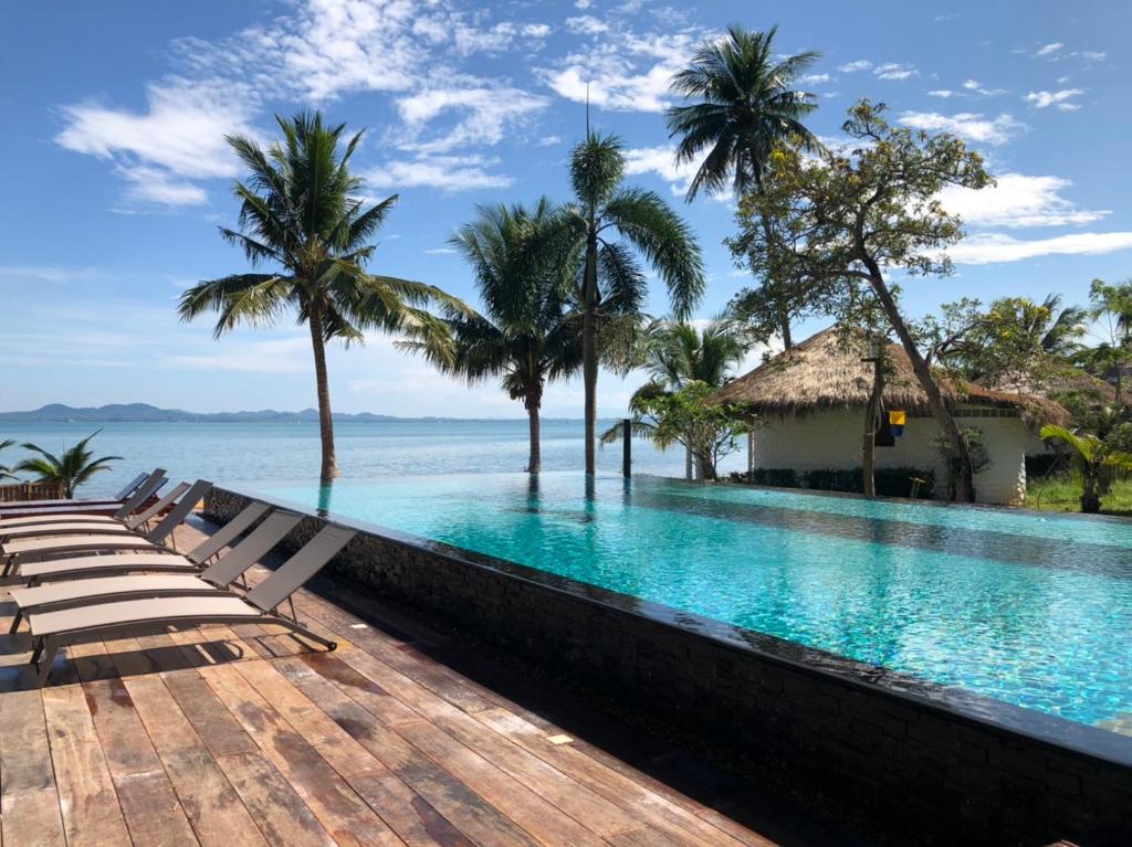 een overloopzwembad van het resort met palmbomen en de oceaan bij Sunrise Beach Resort in Ko Chang