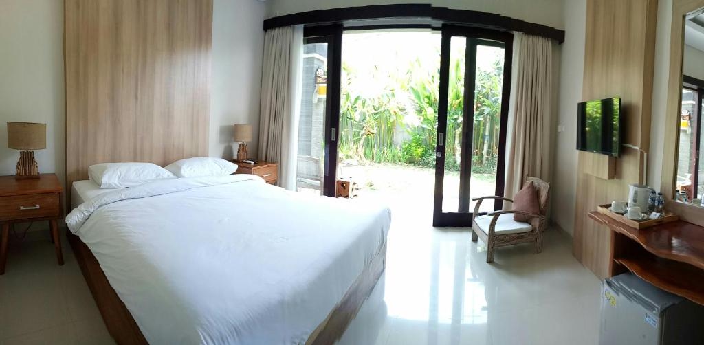 a bedroom with a white bed and a sliding glass door at Guest House Reisya in Nusa Dua