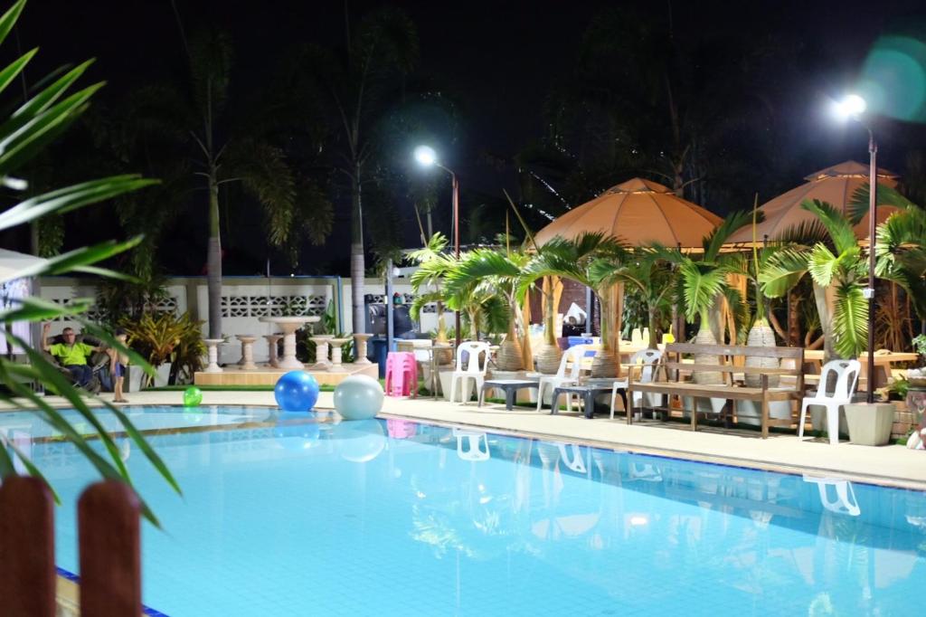 a swimming pool at night with chairs and umbrellas at One-D Homestay in Sattahip