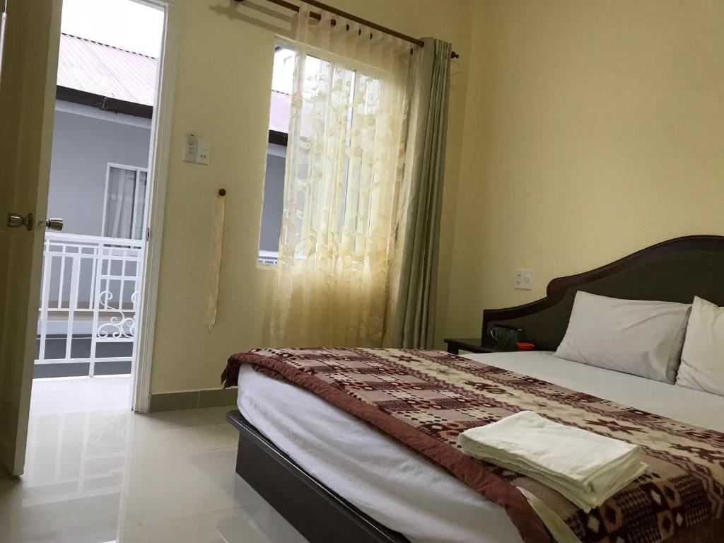 Schlafzimmer mit einem Bett und einem Fenster mit einem Balkon in der Unterkunft Phuong Hong Guesthouse in Da Lat
