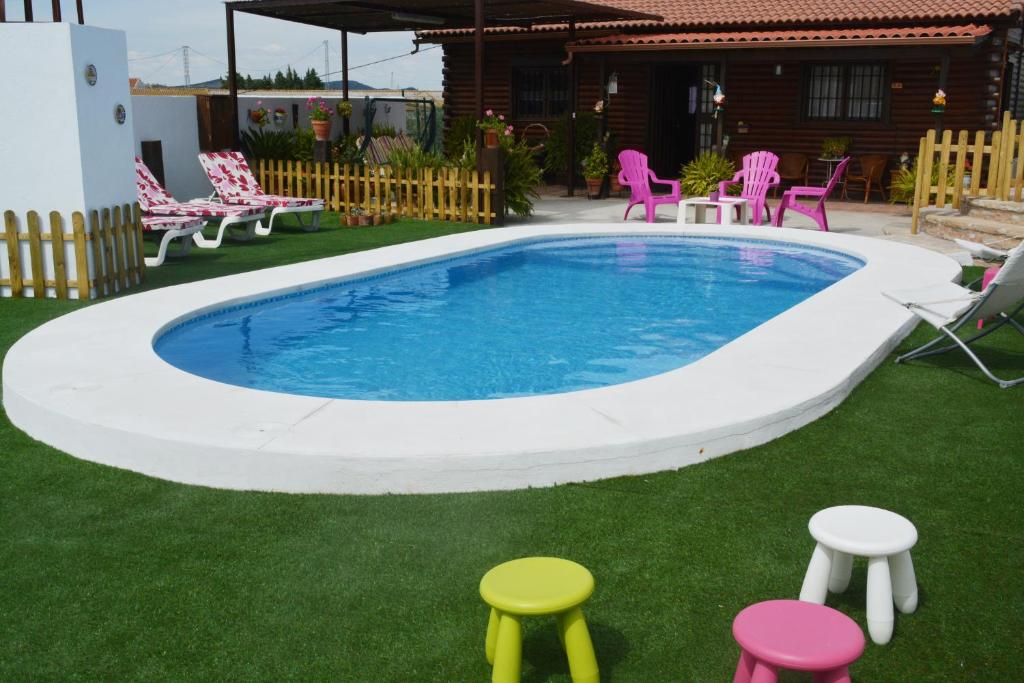 una piscina con taburetes alrededor en un patio en La Casita de Madera, en Ardales