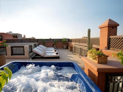una bañera de hidromasaje en un balcón con nubes en Riad Dar Selen, en Marrakech