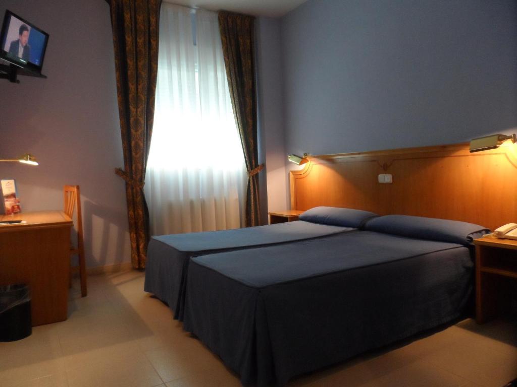 a bedroom with a blue bed and a window at Hotel Rey Arturo Burgos in Villagonzalo-Pedernales