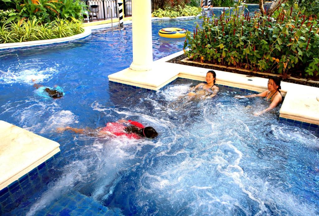 three people in a swimming pool at a resort at Venetian Poseidon Pool Hotel in Jomtien Beach