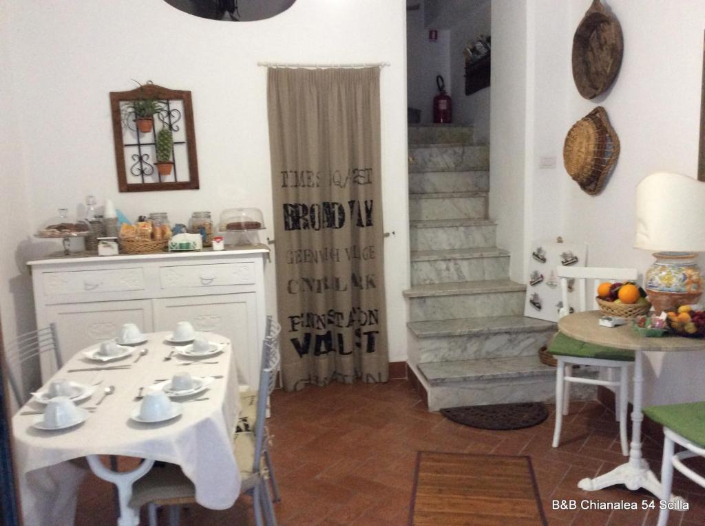 uma cozinha com uma mesa branca, cadeiras e escadas em B&B Chianalea 54 em Scilla