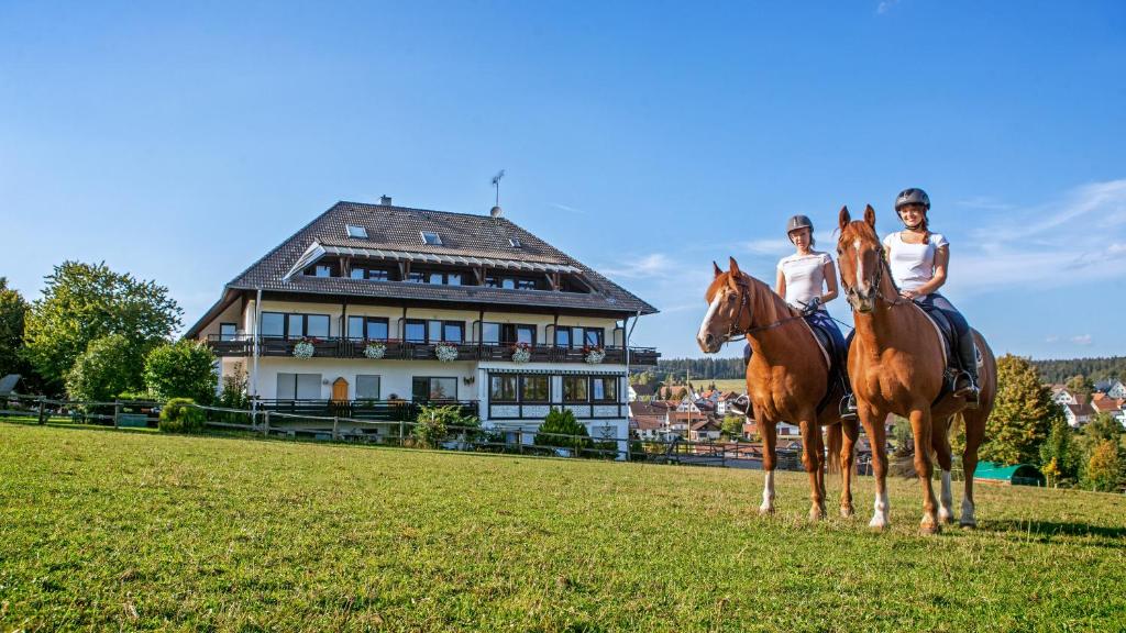 duas pessoas a andar a cavalo em frente a uma casa em Landpension Pferdekoppel - Self Checkin em Seewald