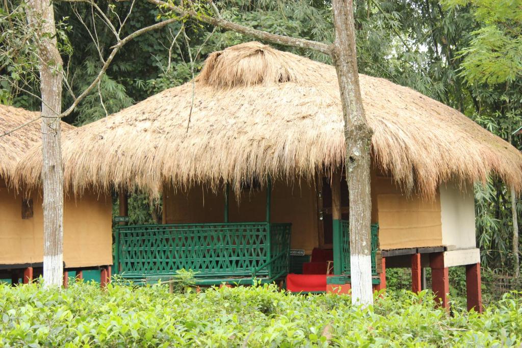 una cabaña con techo de paja y una silla roja en la parte delantera en Nature Hunt Eco Camp, en Kāziranga