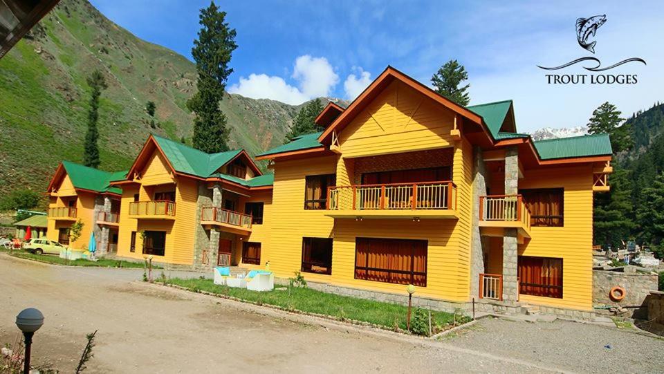 a large yellow building with green roofs at Trout Lodges in Ghumla