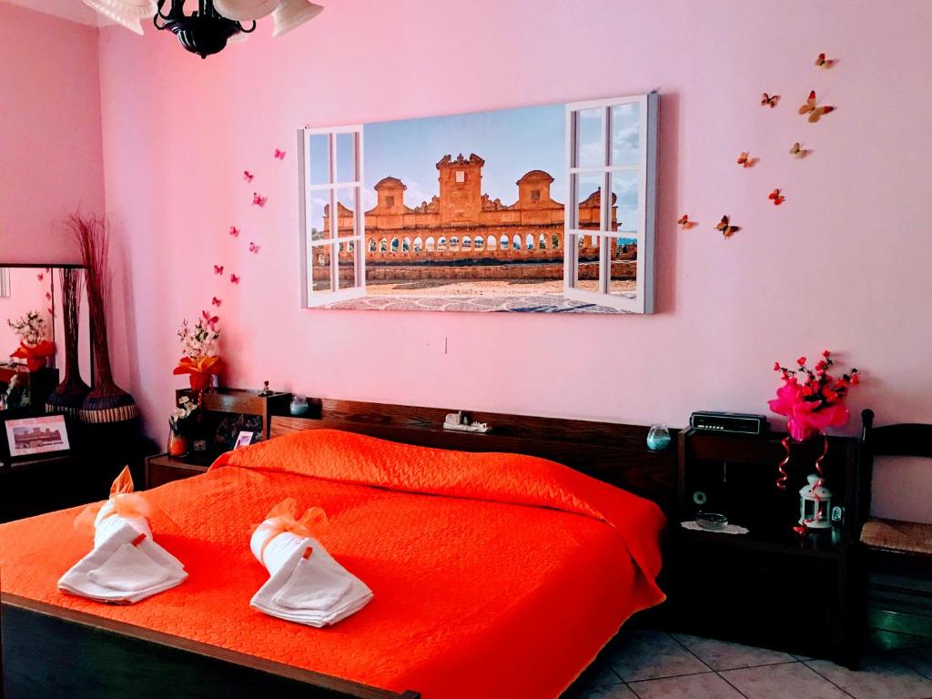 um quarto rosa com uma cama com lençóis vermelhos e uma janela em 24 Cannoli em Leonforte