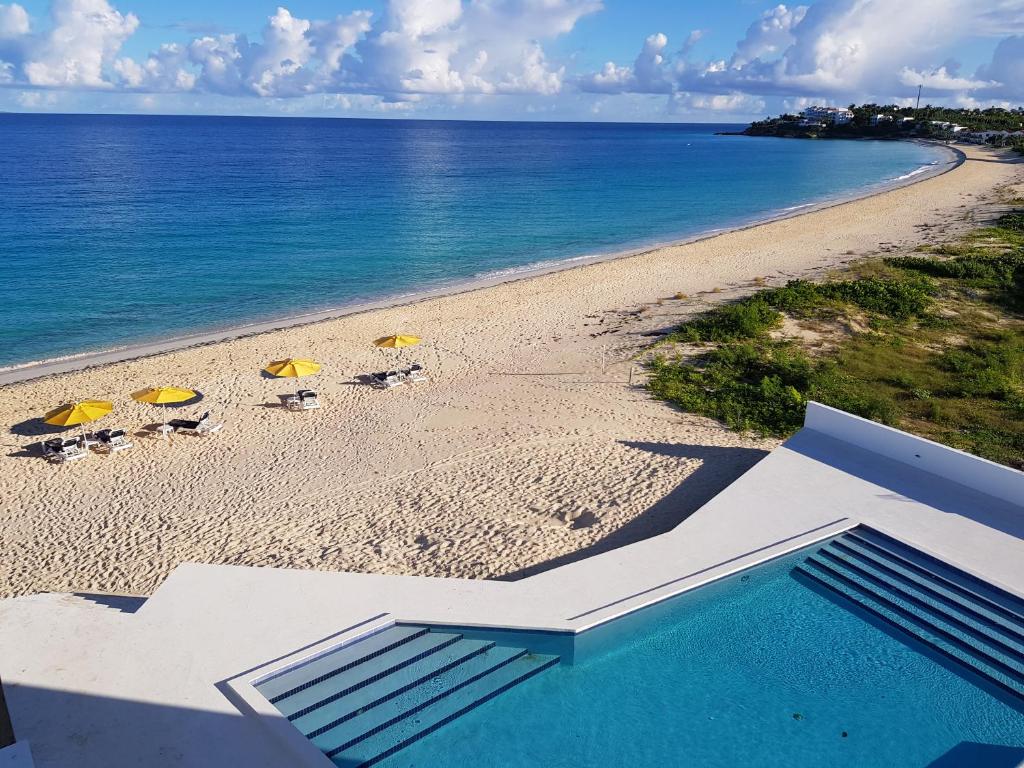 uma vista para uma praia com cadeiras e guarda-sóis em Turtle's Nest Beach Resort em Meads Bay