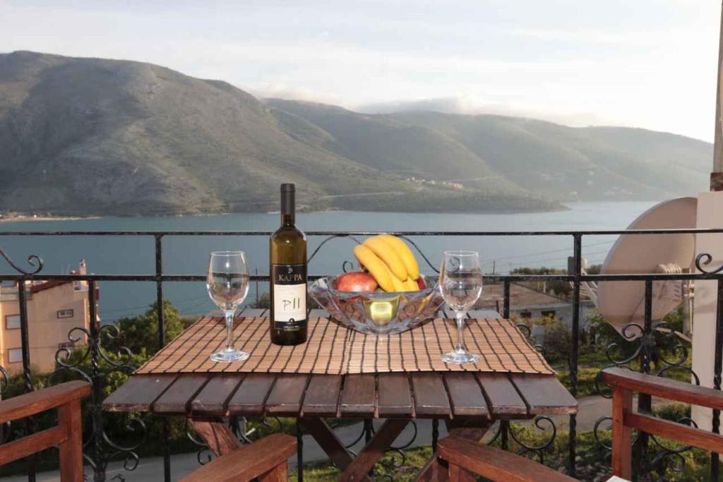 a table with a bowl of fruit and a bottle of wine at Almini Apartments in Plataria