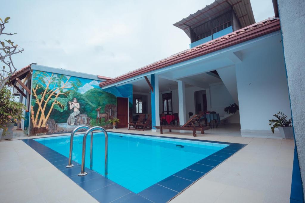 a swimming pool next to a house with a mural at The Cappuccino Hotel in Negombo