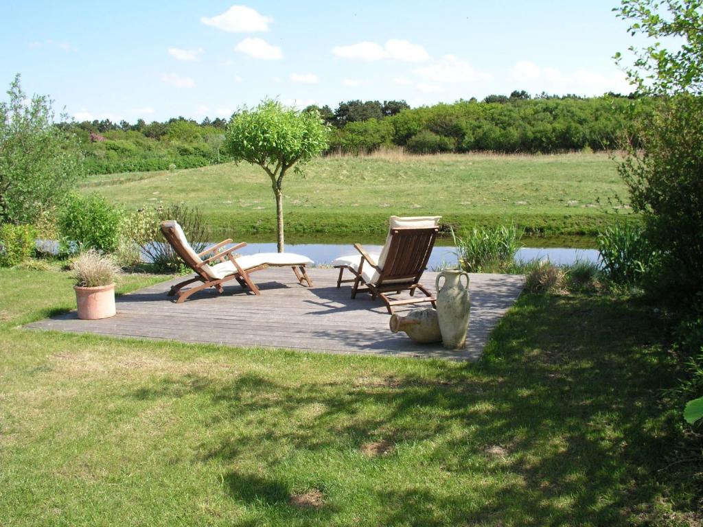 een houten terras met 2 stoelen en een tafel bij Buitenplaats 26 in Callantsoog
