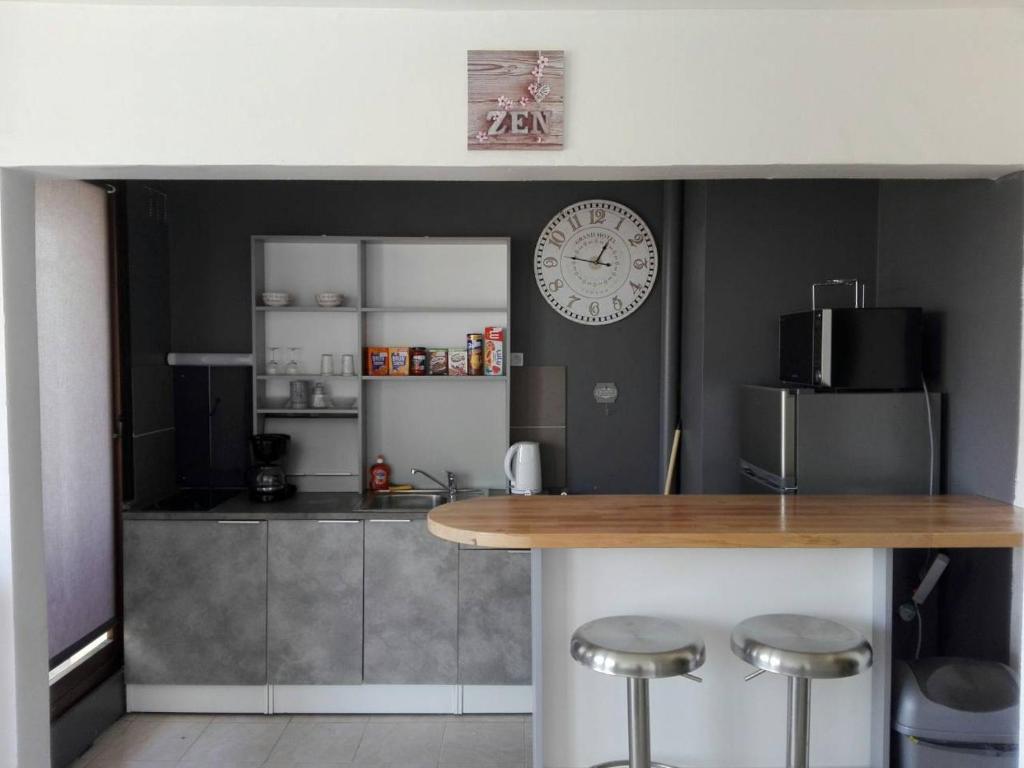 cocina con encimera y reloj en la pared en Fleur d'orchidée studio 99 en Sens