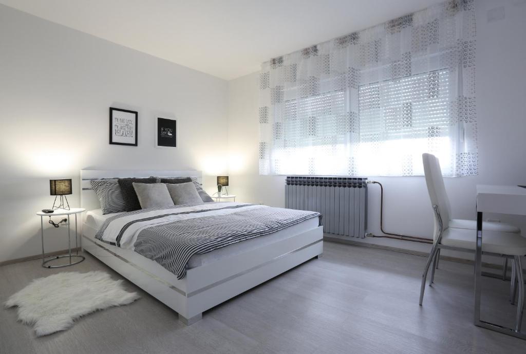 a white bedroom with a white bed and a desk at Imperium Rooms Zagreb Airport in Velika Gorica