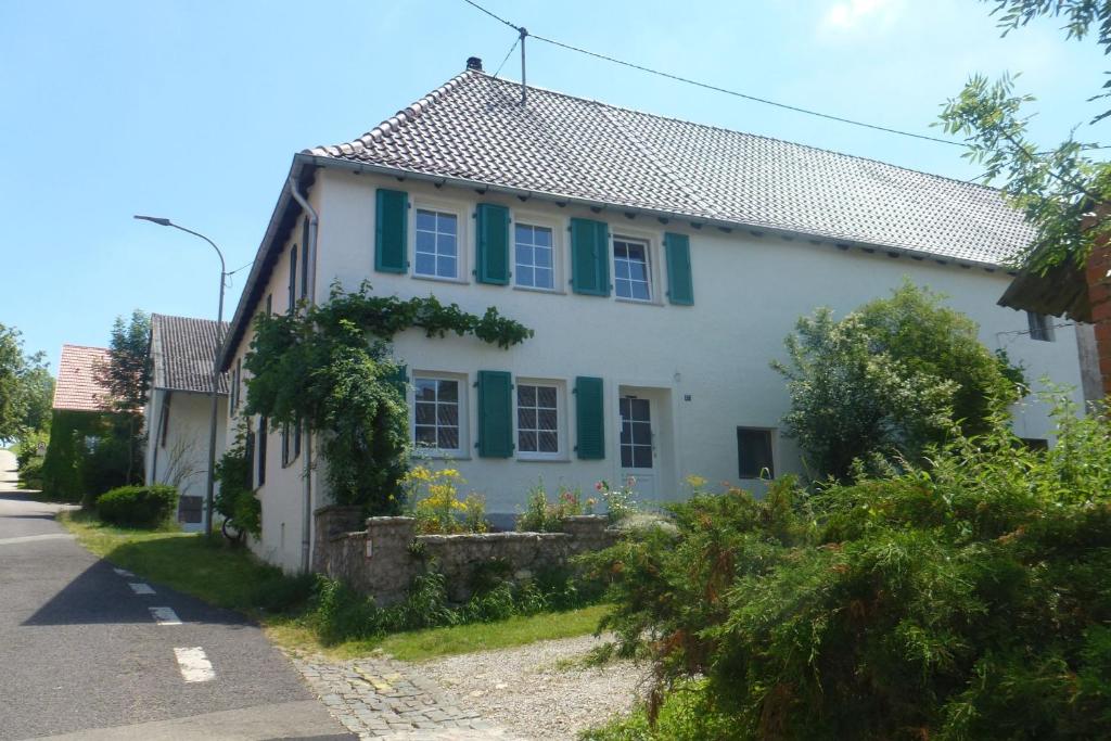 a white house with green shutters on a street at Eulennest, Haus Vogelgesang in Gersheim