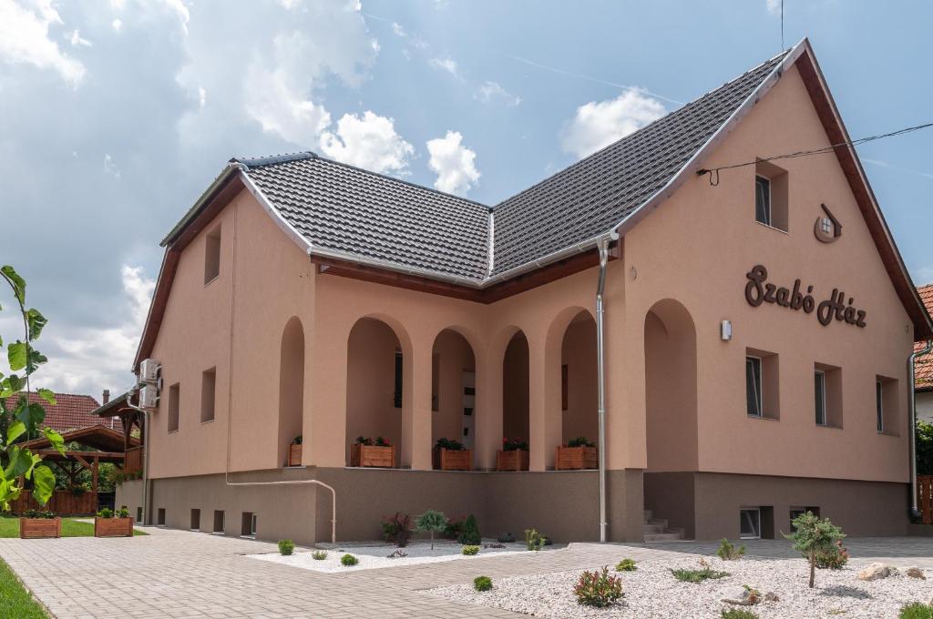 Szabó Ház Tiszafüred في تيسزافوريد: مبنى وردي كبير مع سقف أسود