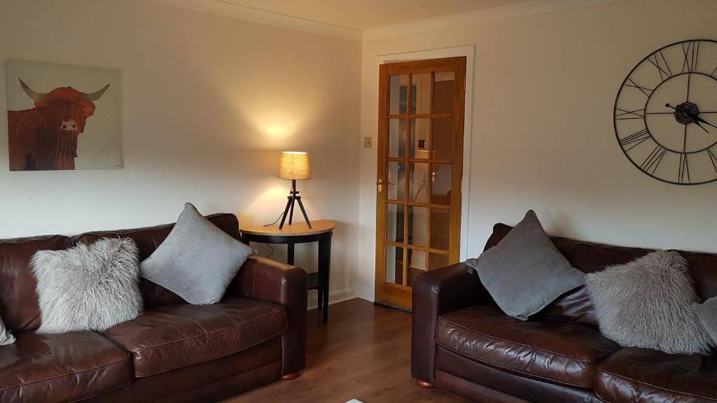 a living room with two leather couches and a clock at Largs stay With Private parking in Largs