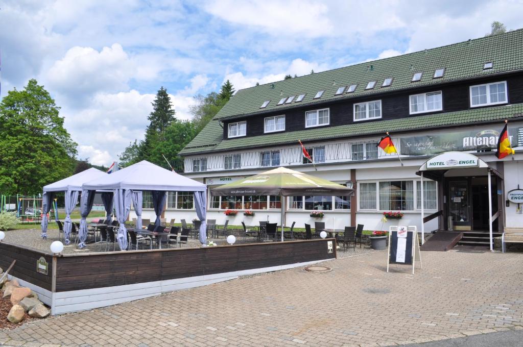 ein Gebäude mit Tischen und Sonnenschirmen davor in der Unterkunft Hotel Engel Altenau in Altenau