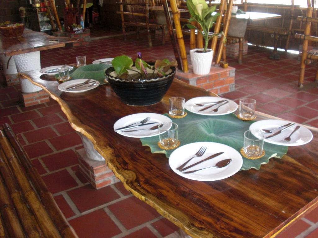 une table en bois avec des assiettes et des verres dans l'établissement Maison en Bambou Phong-Le Vent, à Sa Ðéc