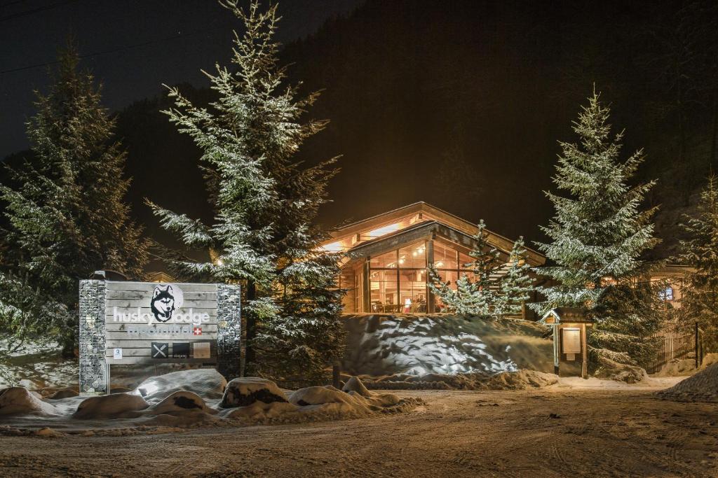 una cabaña de madera en la nieve por la noche en Hüttenhotel Husky Lodge, en Muotathal