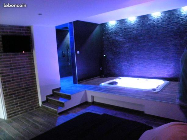 a large bathroom with a tub and a brick wall at chambre romantique avec spa privatif in Ferrière-la-Grande