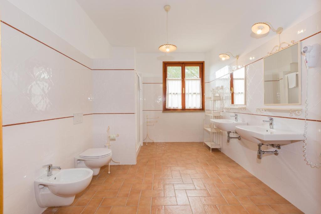 - une salle de bains blanche avec 2 lavabos et 2 toilettes dans l'établissement VILLA LIGUSTRO, à Riparbella