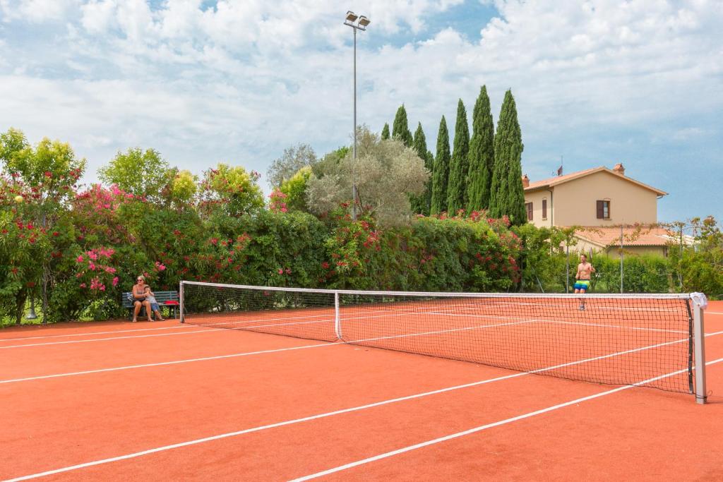 deux personnes jouant au tennis sur un court de tennis dans l'établissement VILLA LIGUSTRO, à Riparbella