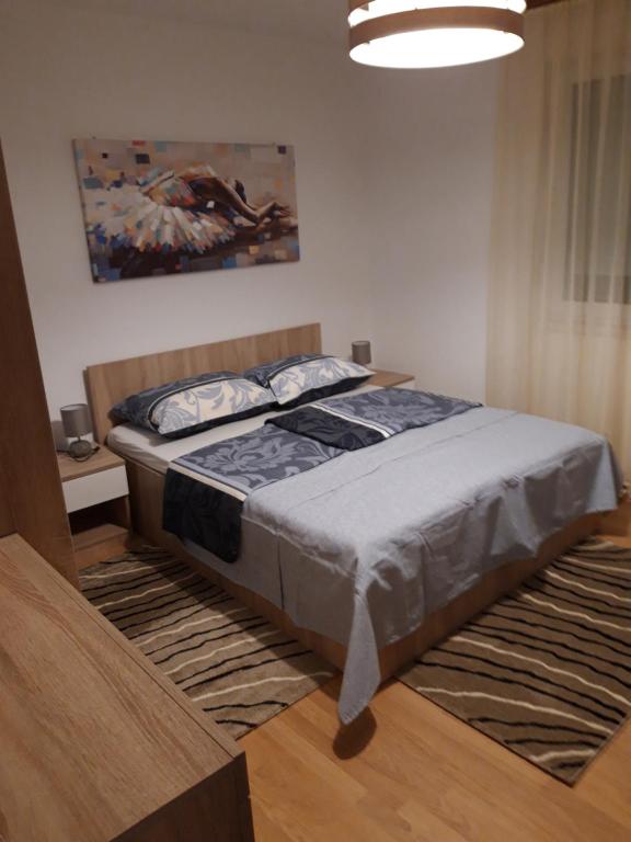 a bedroom with a bed and a painting on the wall at Apartman Centros in Osijek