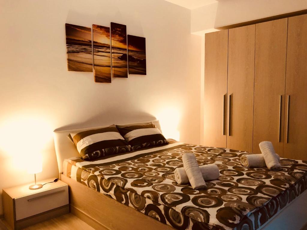 1 dormitorio con 1 cama con mesita de noche y una pintura en Eme Apartments, en Brasov