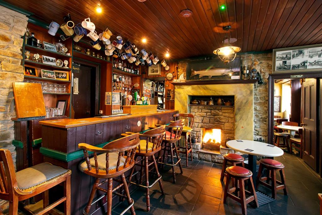 a bar with a fireplace and tables and chairs at The Rusty Mackerel in Teelin