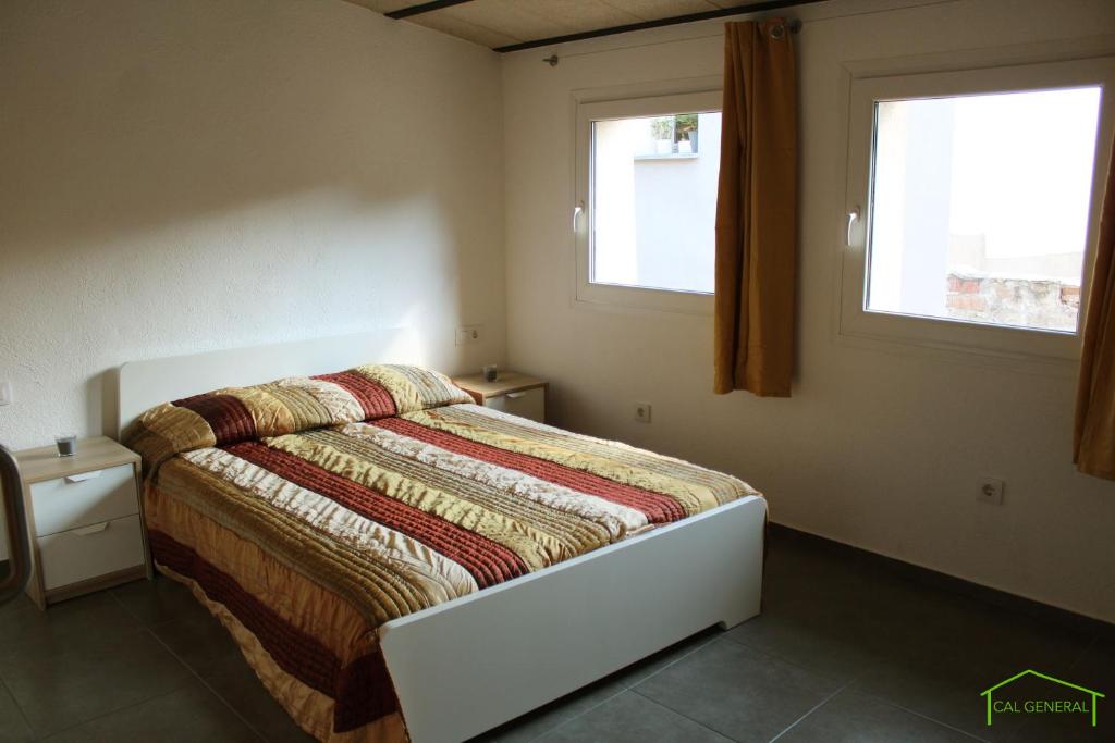 a bedroom with a bed and two windows at CAL GENERAL in La Cellera de Ter