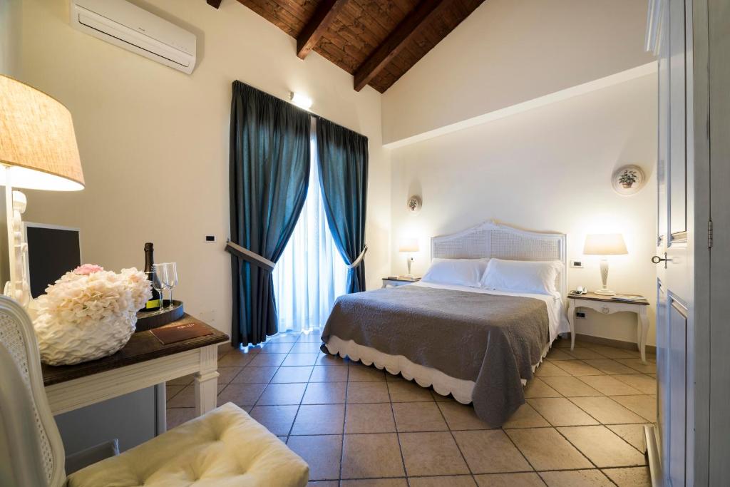 1 dormitorio con 1 cama con cortinas azules y escritorio en Tenuta D'Amore, en San Mango Piemonte