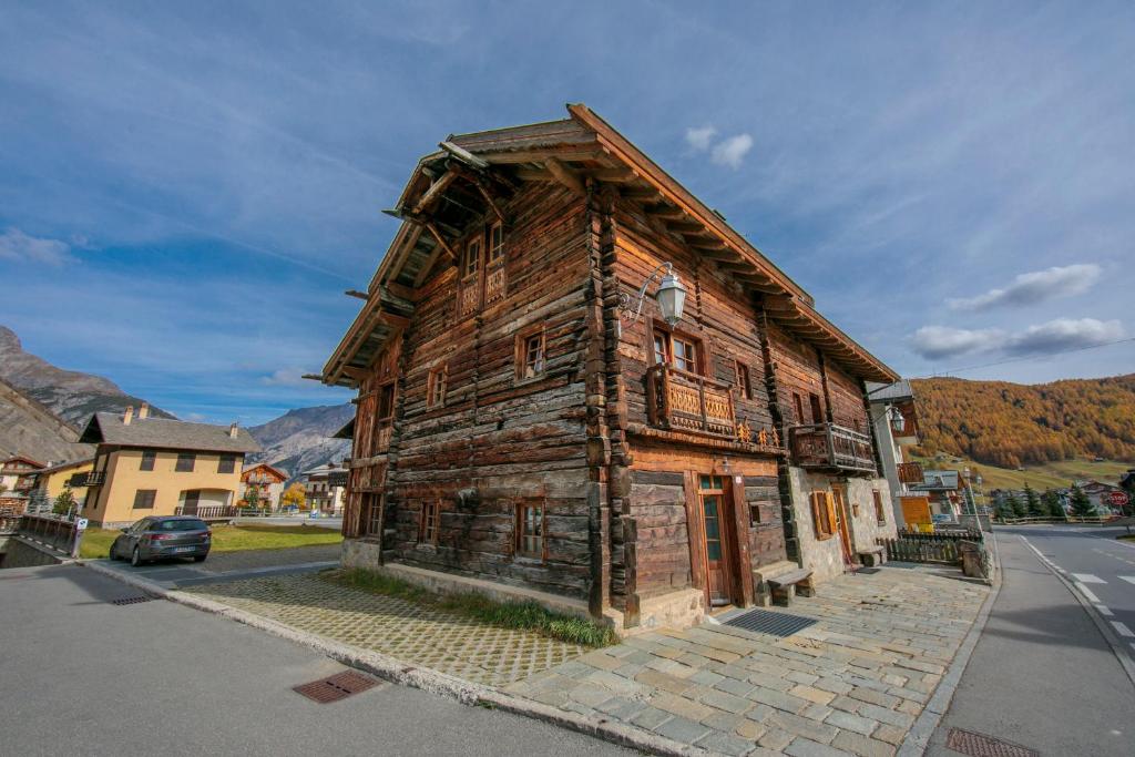 un antiguo edificio de madera al lado de una calle en Chalet Menin - Happy Rentals, en Livigno