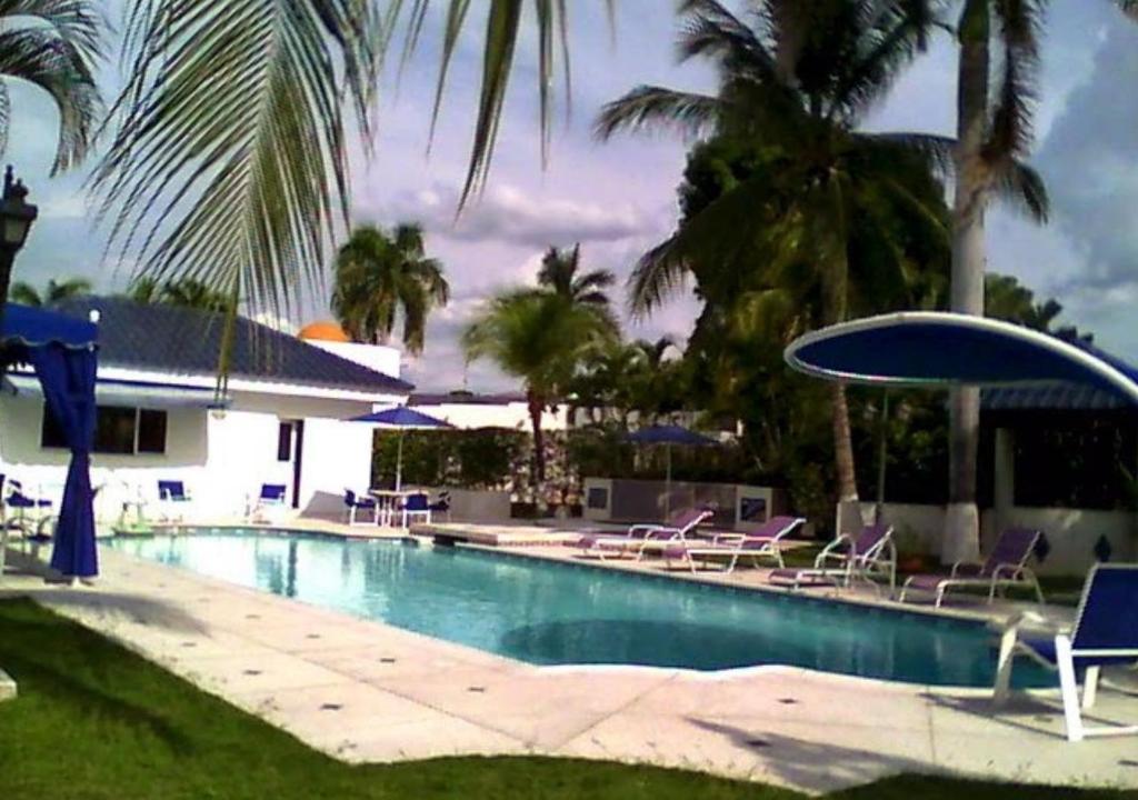 a swimming pool with chairs and umbrellas and palm trees at Casa Quinta PeÃ±on para grugos Girardot in Girardot