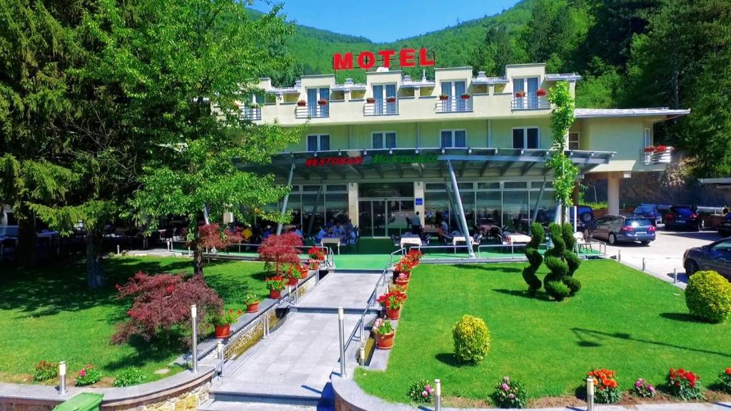 a hotel with a garden in front of a building at Motel Maksumić in Jablanica