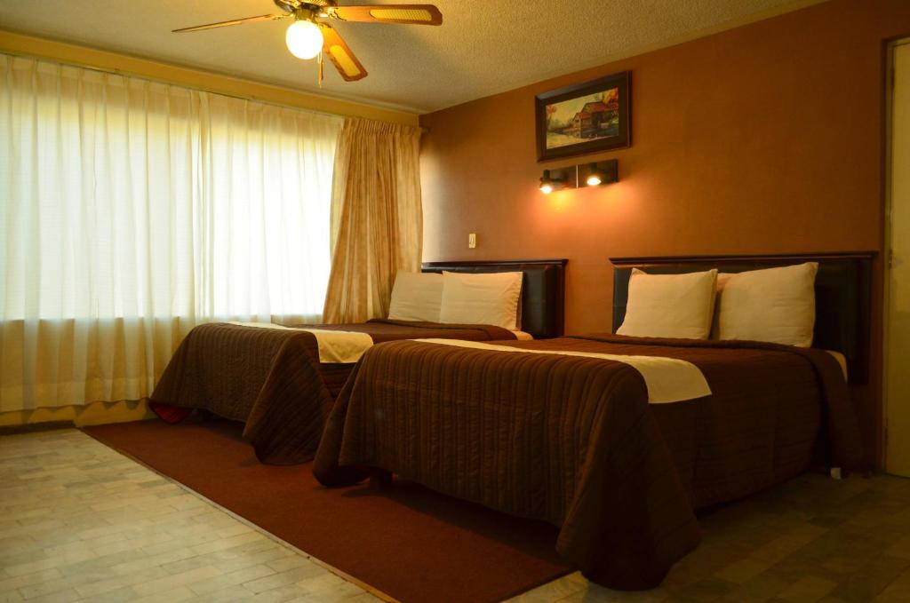 a hotel room with two beds and a window at Hotel Flamingo Kristal in Irapuato