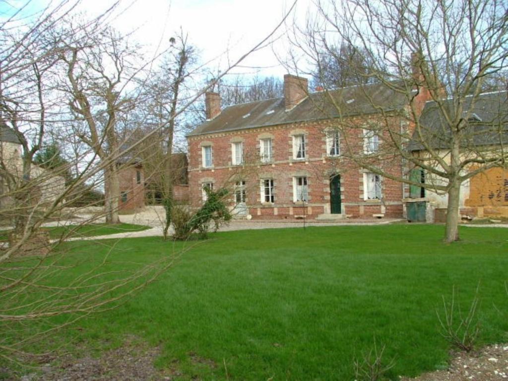 une grande maison en briques avec une pelouse verte en face de celle-ci dans l'établissement Chez Francine et Xavier, à Froissy
