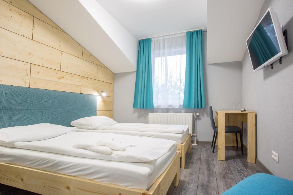 Habitación con 3 camas, mesa y TV. en Penzión Squash en Liptovský Mikuláš