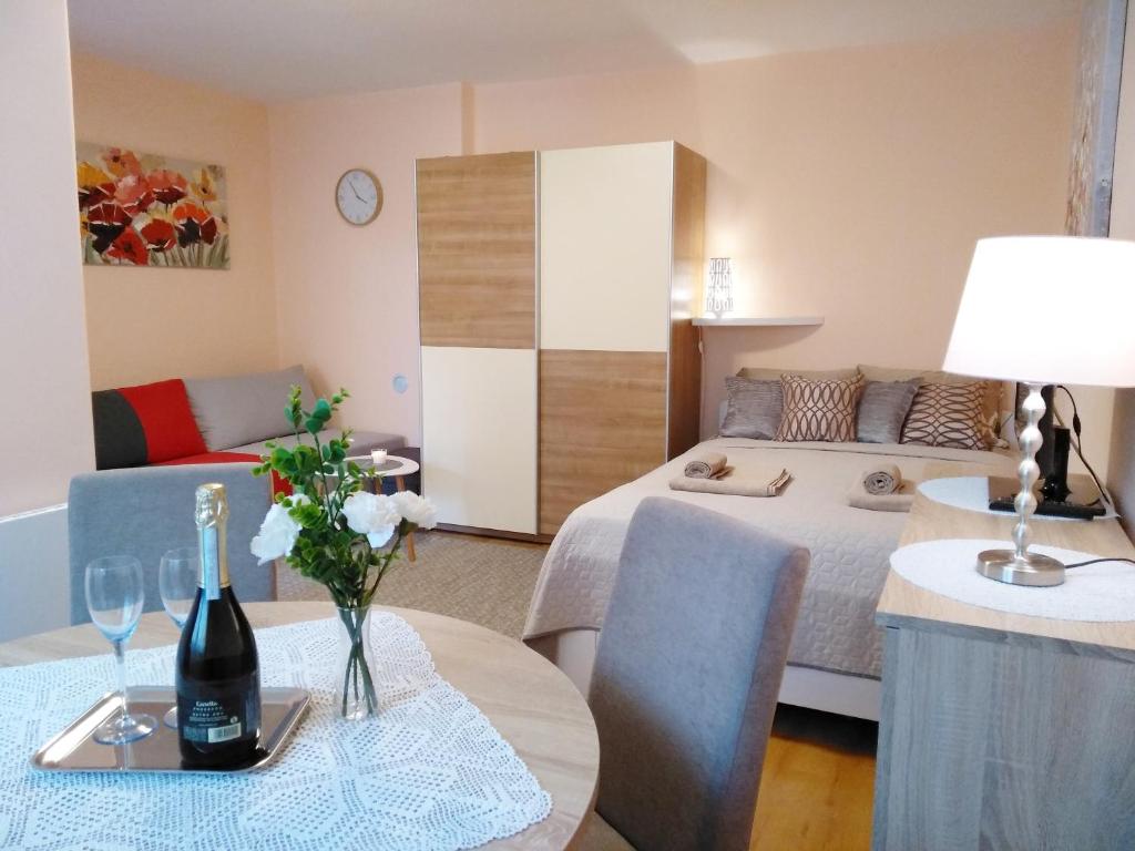 a room with a bed and a table with a bottle of wine at Sunray Studio Apartment in Zagreb