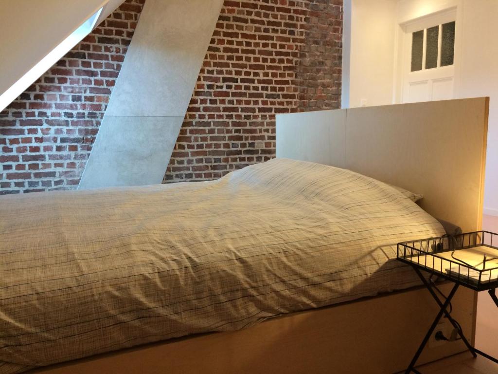 a bed in a room with a brick wall at Nelly in Ypres