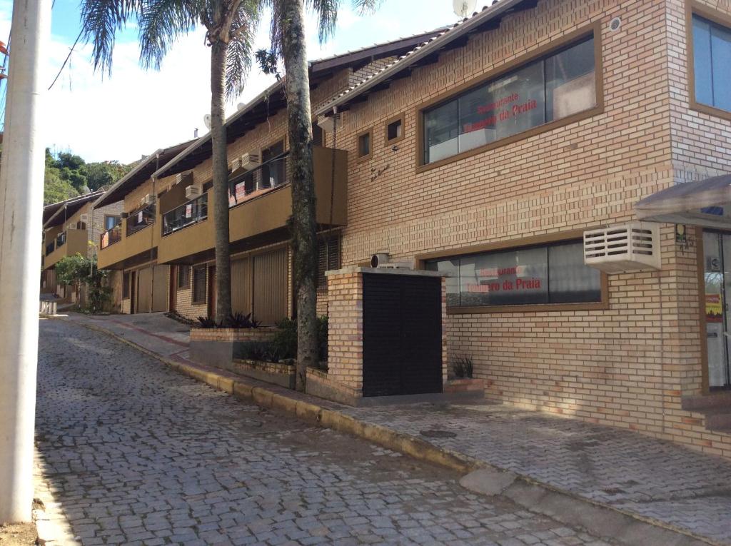 a brick building on a street with palm trees at Apartamento Costa Esmeralda in Bombinhas