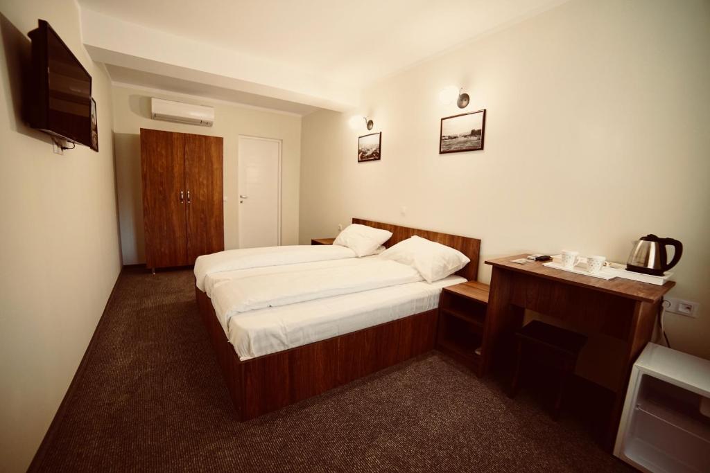 Habitación de hotel con 2 camas y escritorio en Pensiunea Rustic, en Hunedoara