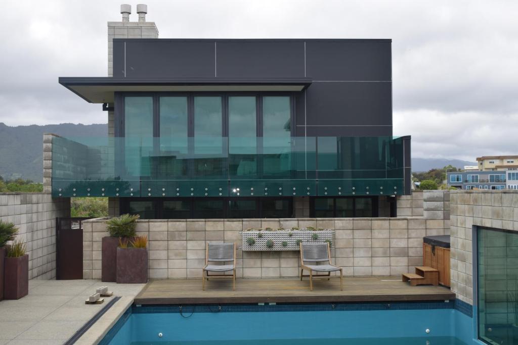 une maison avec une piscine et deux chaises dans l'établissement 157 Field Way Luxury Lodge, à Waikanae