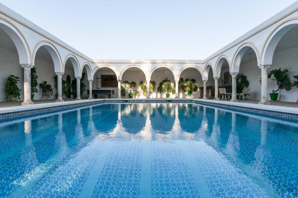 een zwembad in een gebouw met blauw water bij Villa del Manzano in Villanueva del Ariscal