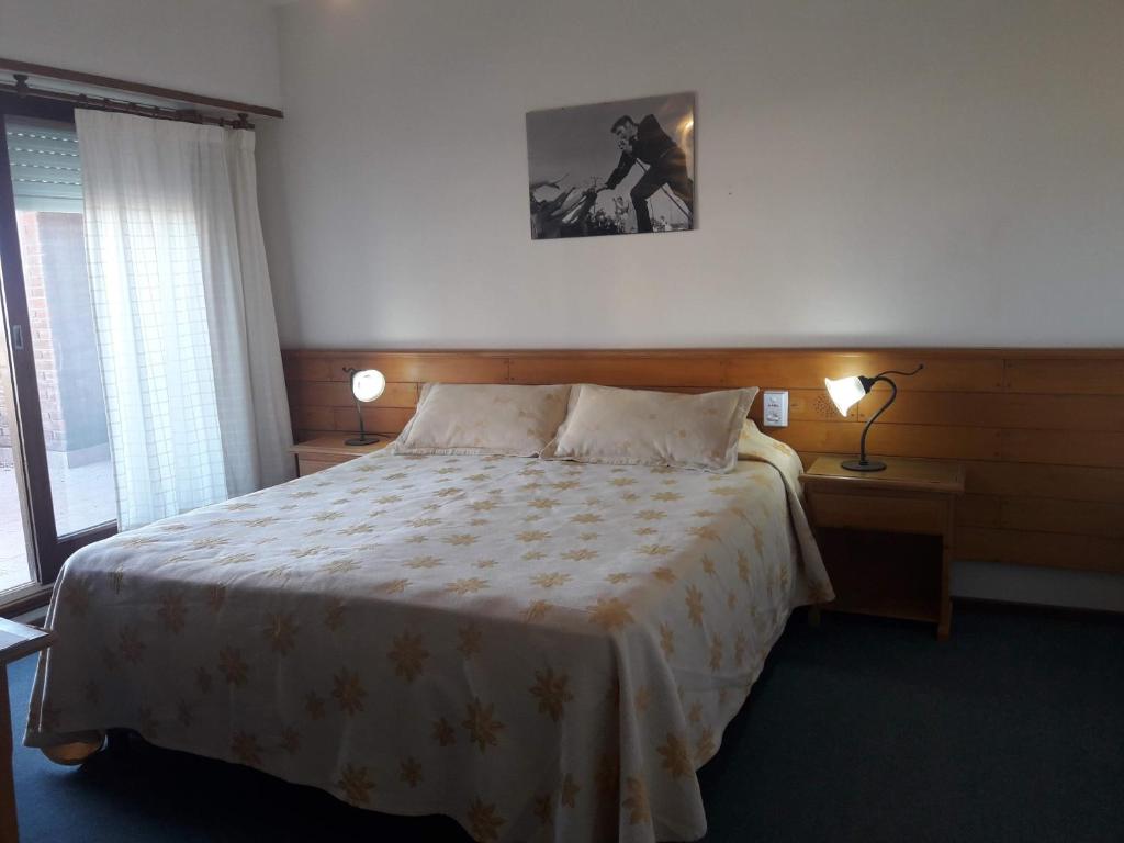 Un dormitorio con una cama y dos lámparas y una ventana. en Hotel Montecarlo, en Villa Gesell