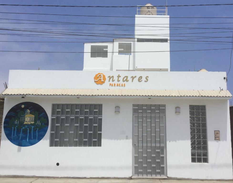 a white building with a lighthouse in the background at Antares Paracas in Paracas