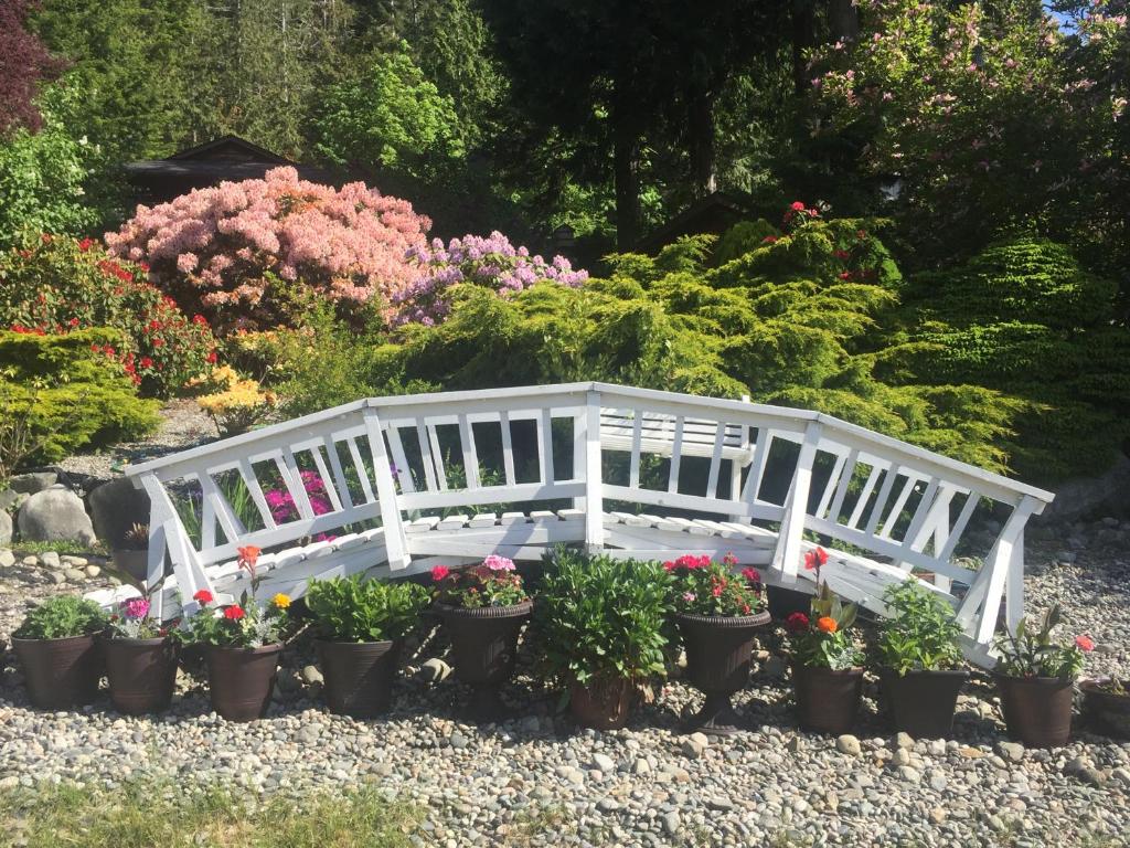 a white bench in a garden with potted plants at Garden Bridge House in Sechelt
