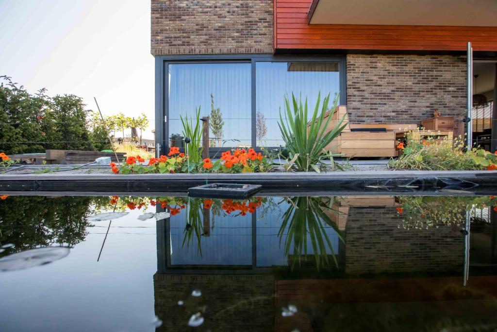 een huis met een reflectie in het water bij Amsterdam Area Residence Oosterwold in Almere